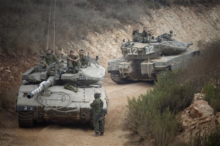 Israeli soldiers sit on a tank Wednesday near the site of an exchange of fire between Israeli and Lebanese troops.